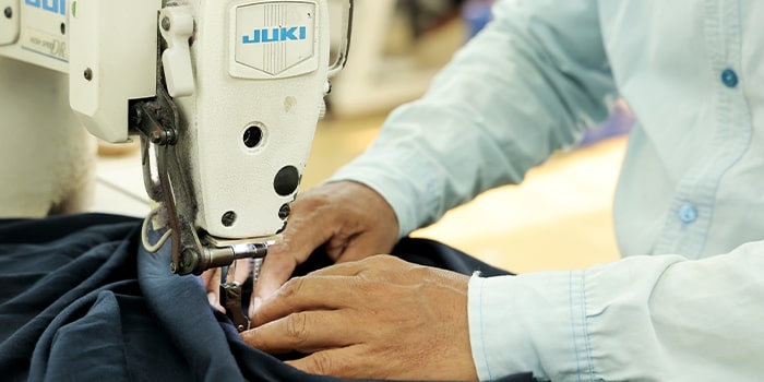 Worker operating industrial sewing machine stitching fabric